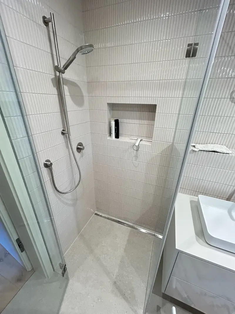 Dusche mit hellen, fein geriffelten Wandfliesen und eingelassener Ablagenische