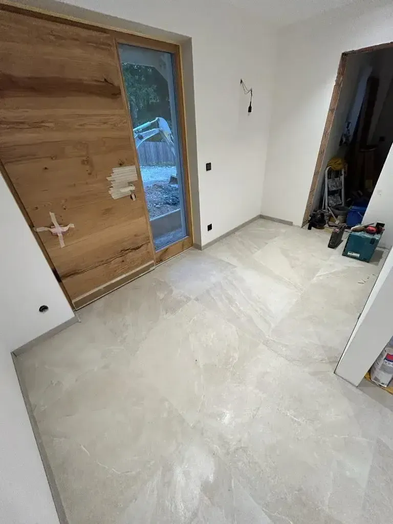 Großformatige beige Bodenfliesen mit passenden Sockelfliesen im Eingangsbereich