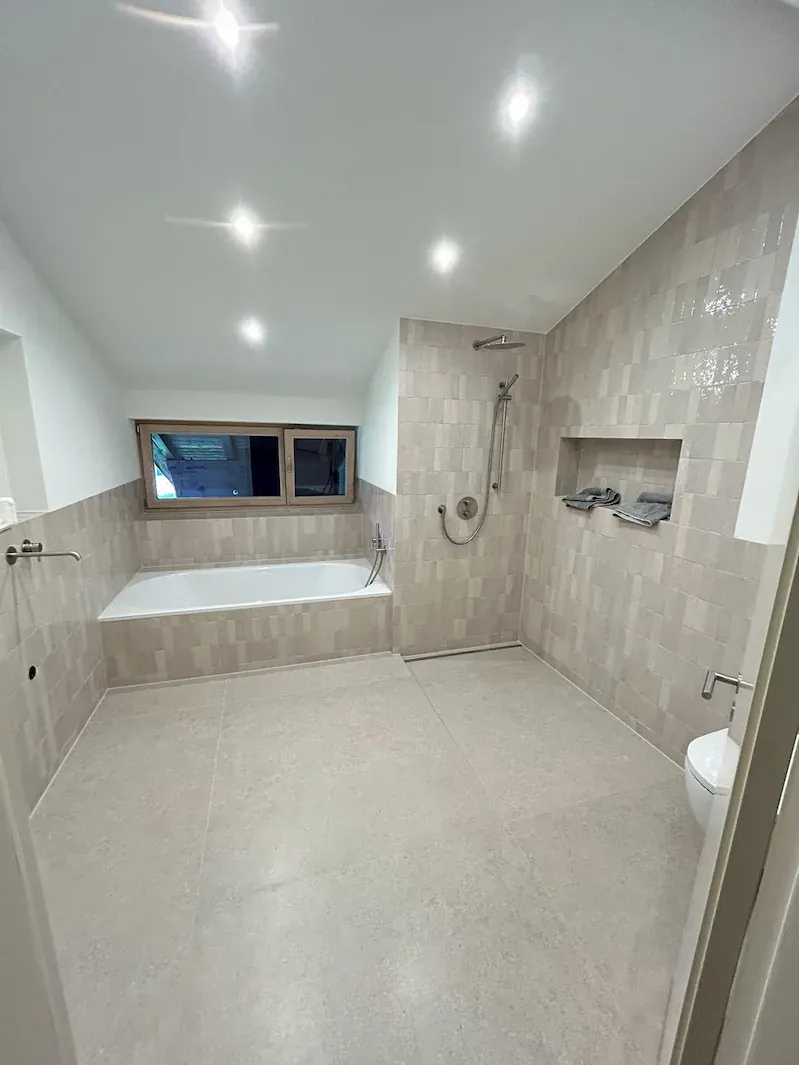 Badezimmer mit beigen Wandfliesen, bodengleicher Dusche und gefliester Badewannenverkleidung